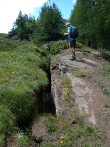 1.Apertura di un trench lungo la cresta rocciosa che sovrasta la bassa Val di Rhêmes, versante sinistro. La roccia è calcescisto (metasedimento oceanico) con giacitura immergente a W (destra nella foto) dove si stende il bosco verso Les Combes d’Introd.