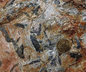 05. Particolare del micascisto eclogitico. Visibili le lamelle di mica bianca, il quarzo e grossi cristalli blu scuro di glaucofane, un anfibolo di grande profondità e bassa temperatura.